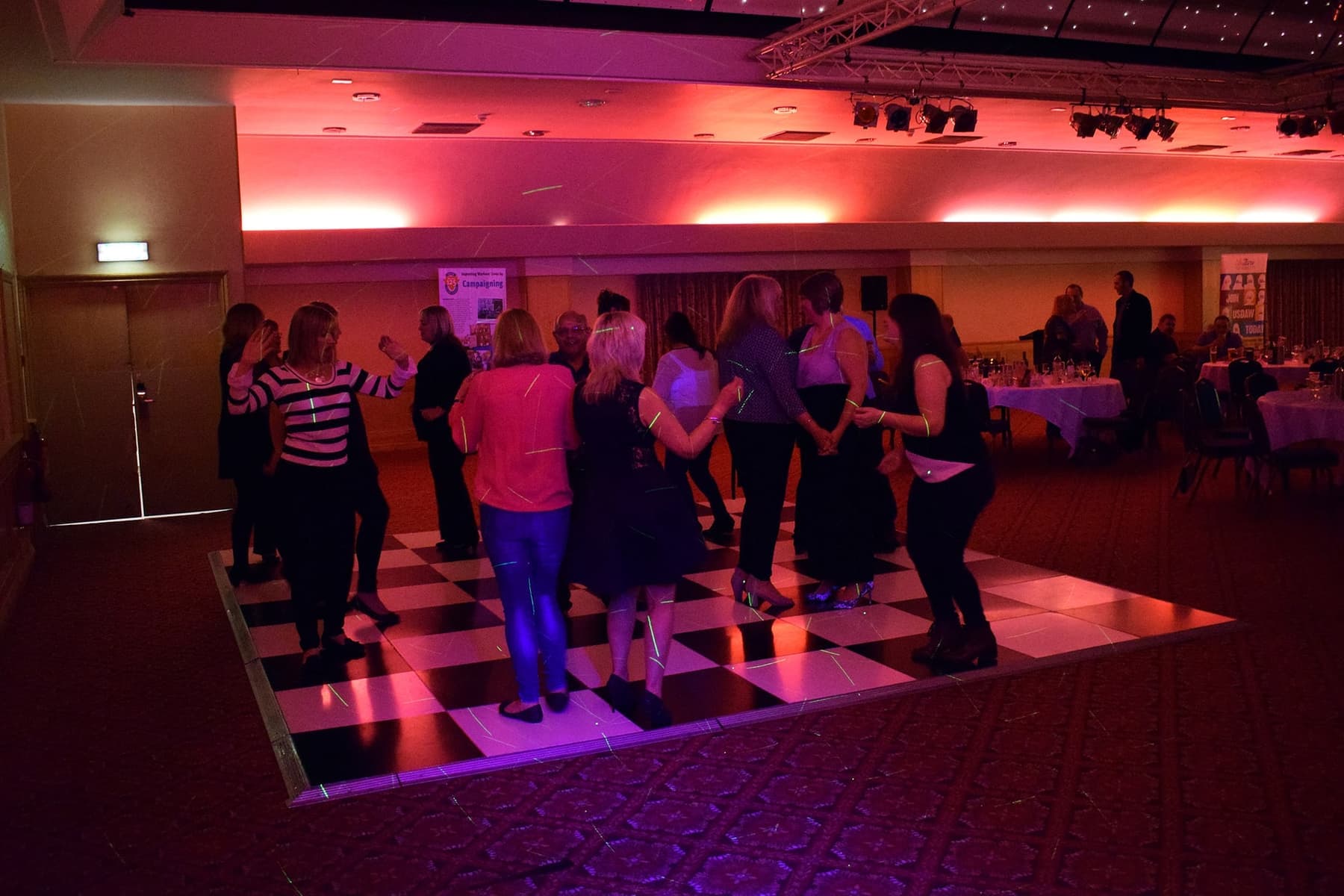 A packed dance floor under pink and blue lights