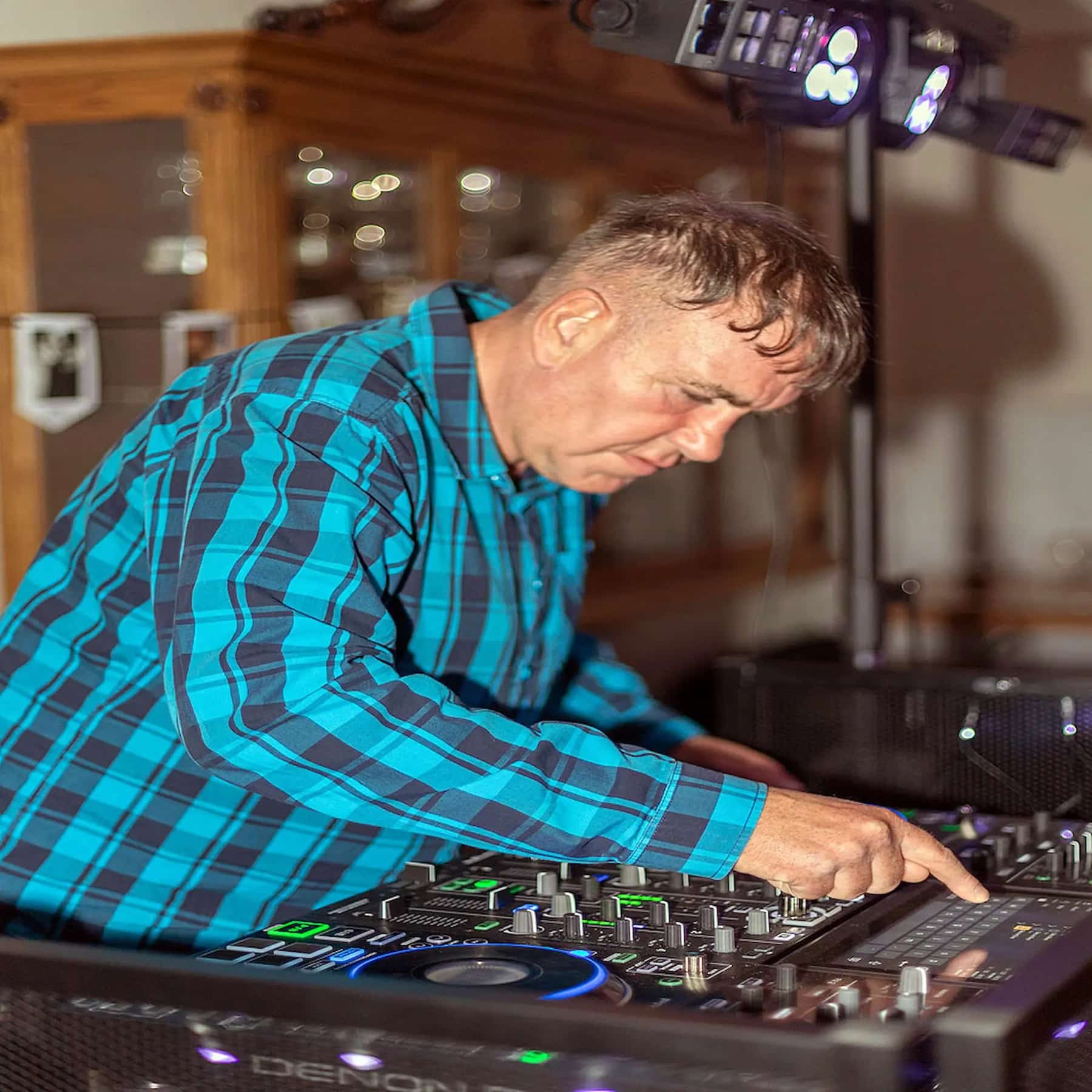 A DJ adjusting a Denon controller at the decks