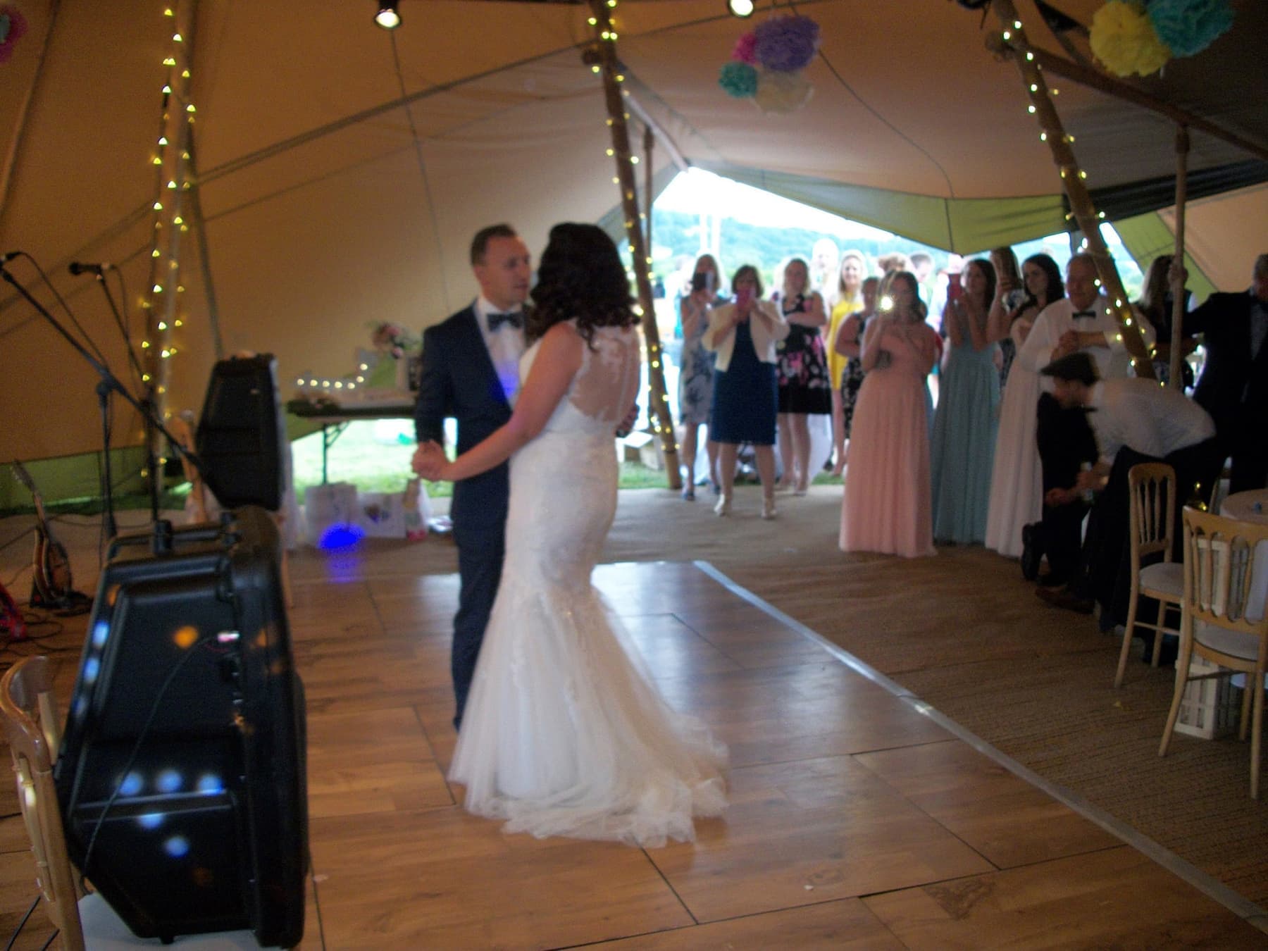 A bride and groom's first dance in a marquee, guests watching from the edge of the floor